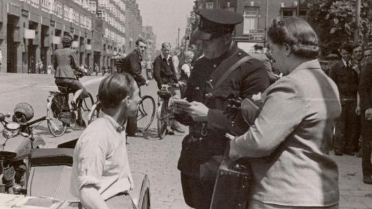 Een politieagent bekeurt op de Vijzelgracht een jongen, 1942